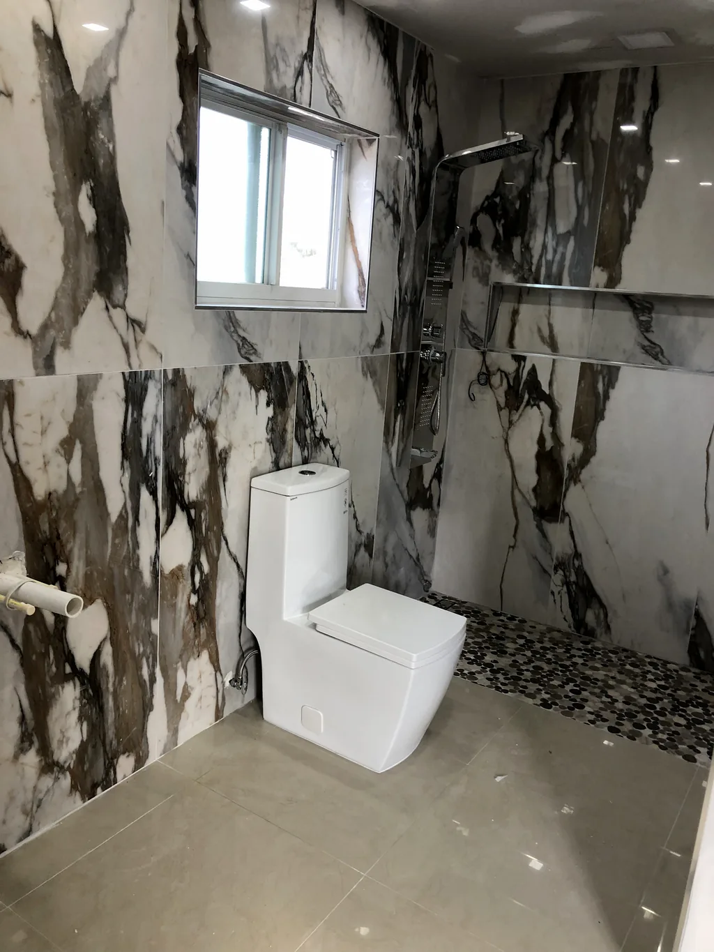 Bathroom finished in dramatic book-matched calacatta marble-look porcelain across the walls