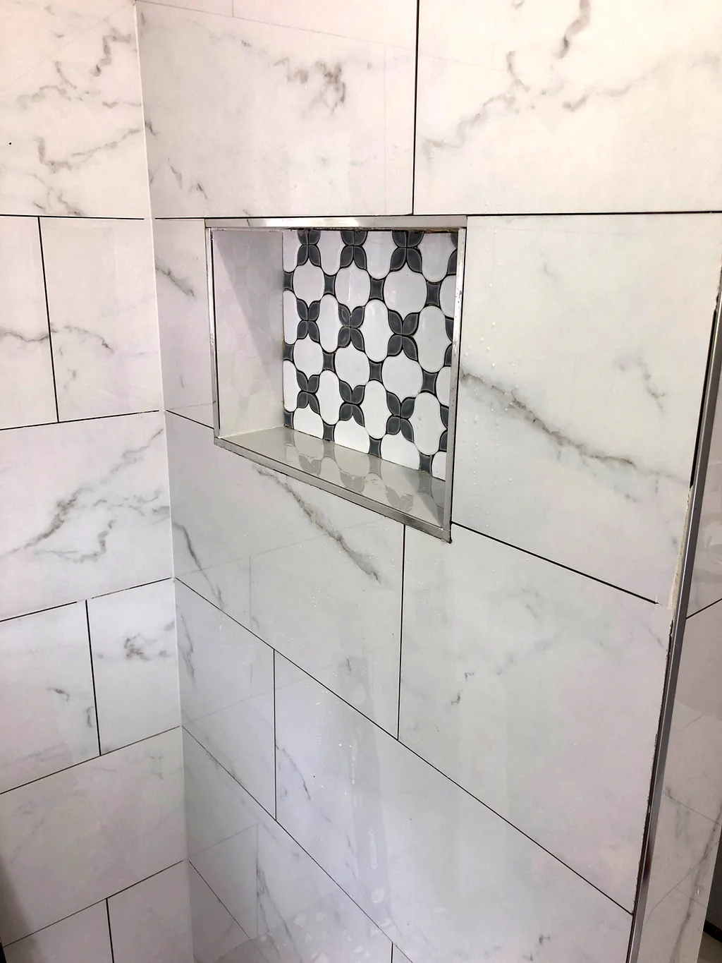 Large-format marble-look floor tile with a patterned decorative inset panel