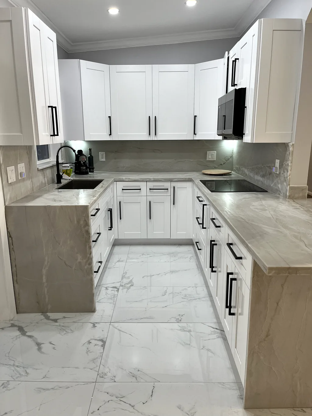 Finished white shaker kitchen with marble-look quartz countertops, black hardware and a full-height stone backsplash