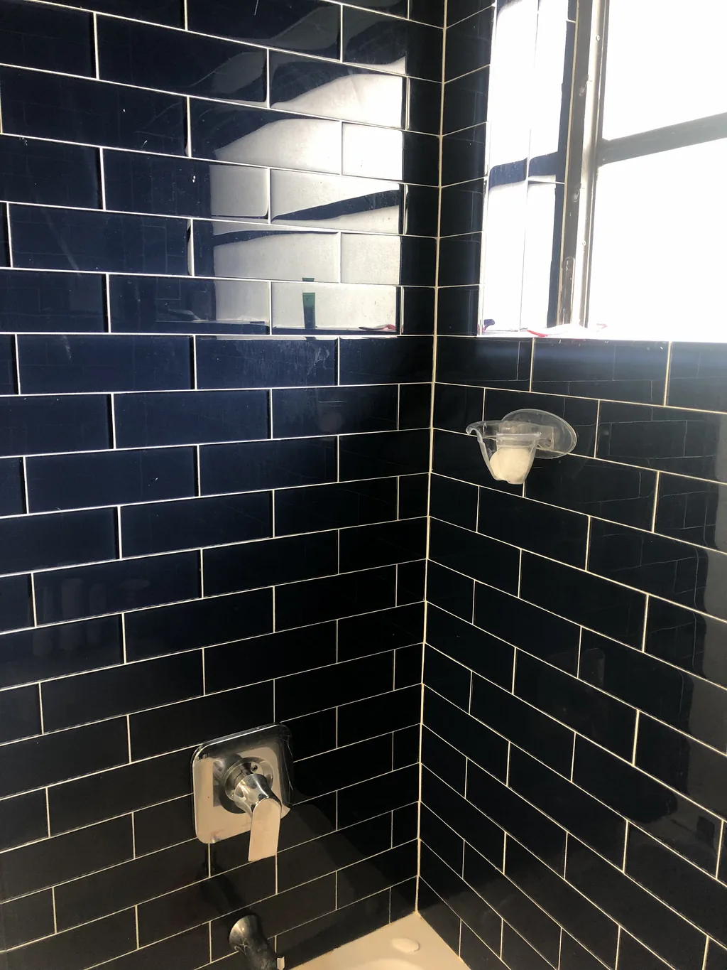 Deep navy subway tile shower enclosure laid in a running bond with a recessed niche